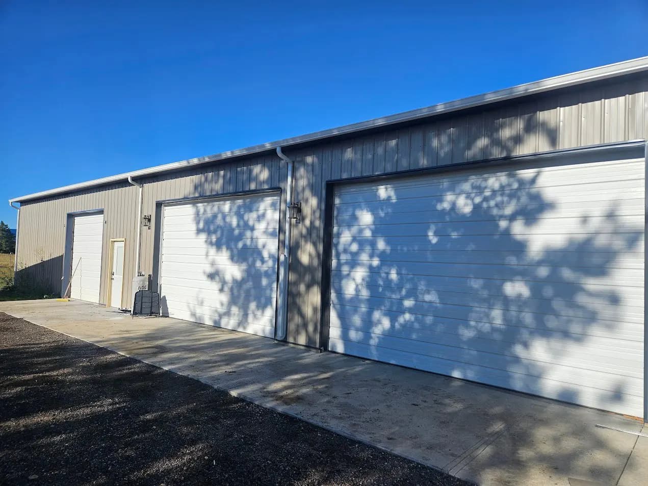 Seamless gutters along a steel shop building with three garage doors