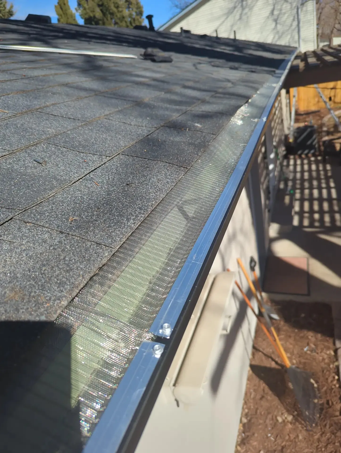 Gutter guard installed along the edge of a shingle roof